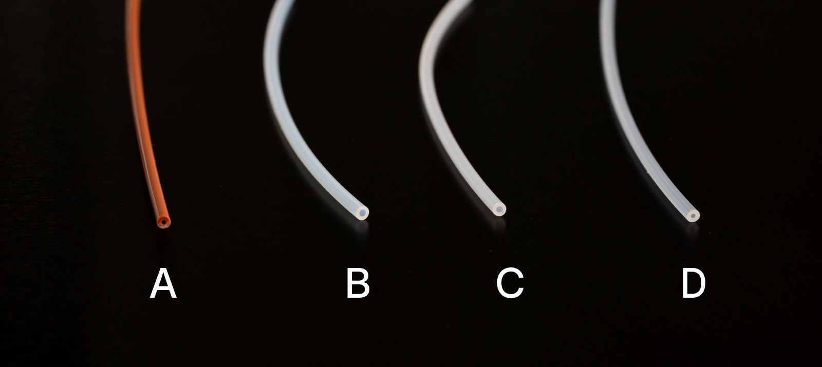 Four types of 1/16" diameter capillary tubing. From left to right: PEEK - labelled A, PTFE - labelled B, ETFE - labelled C, and PFA - labelled D.