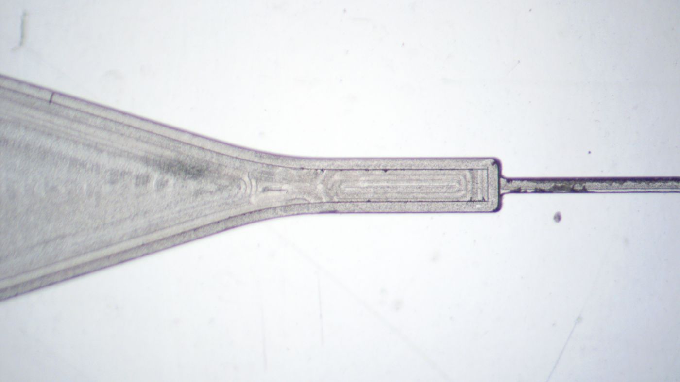 Close-up of a micromilled capillary valve and sloped microfluidic channel. The surfaces are somewhat smooth with clearly visible tool marks.
