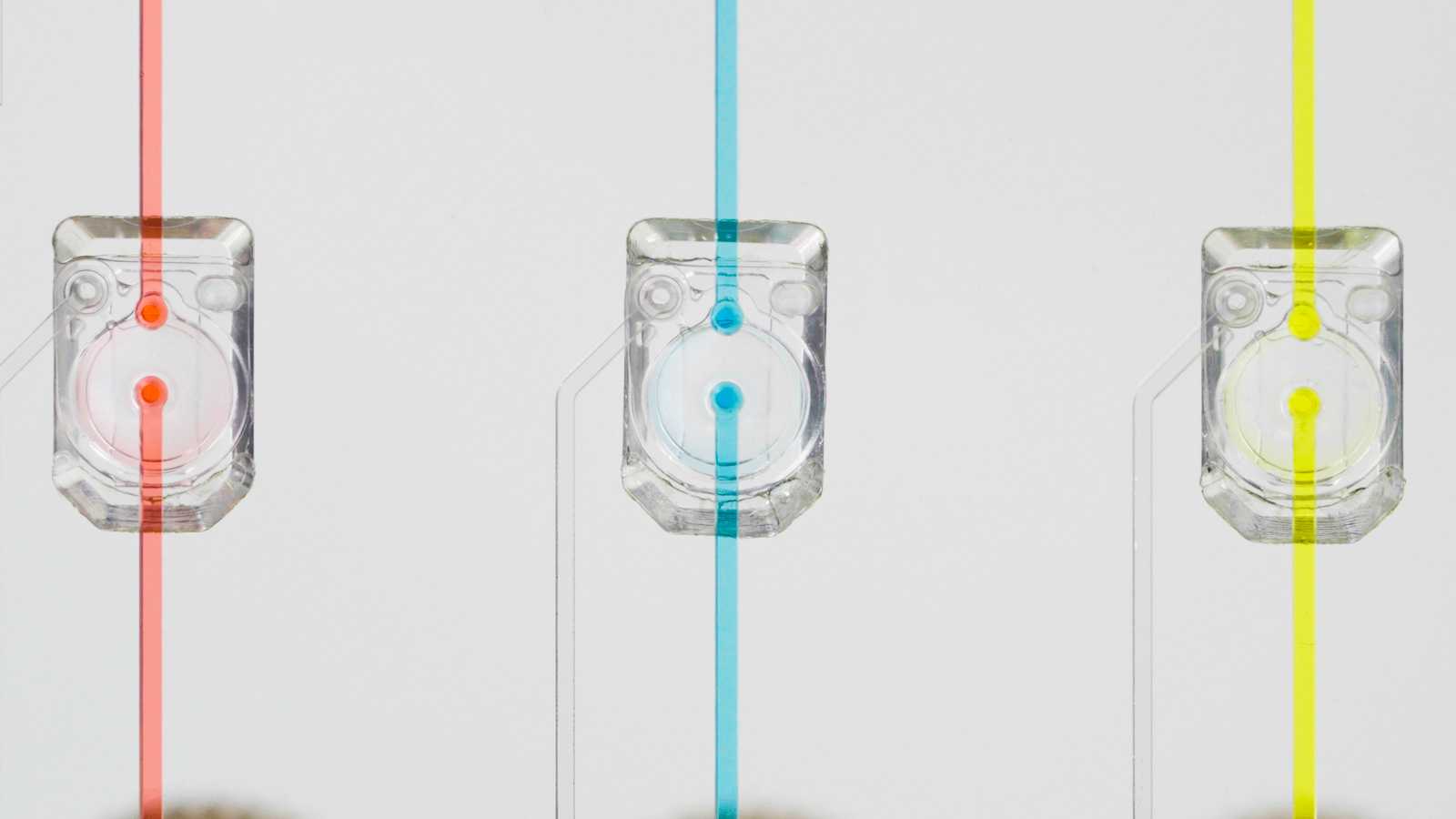 Close-up of three MV-2 microvalves on a microfluidic device with red, blue, and yellow fluid flowing through them, respectively.
